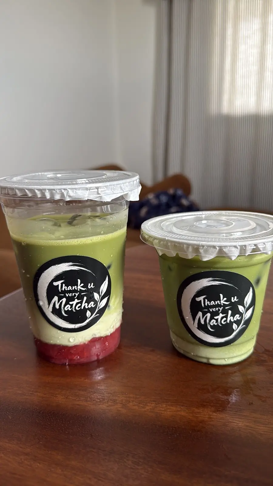 Two iced strawberry matcha lattes on a wooden table